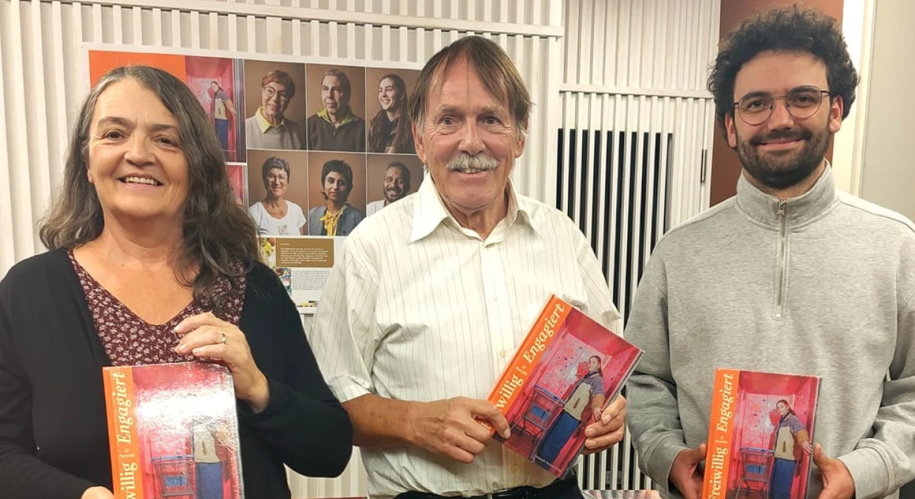 Das Bild zeigt drei der Portraitierten mit dem Buch in der Hand.