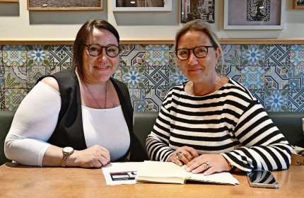 Foto der Freiwilligen Mariann Ebeling mit Mentee Patricia Neumann. Die beiden sitzen in einem Café an einem Tisch. Vor ihnen liegen Notizen zur Besprechung.