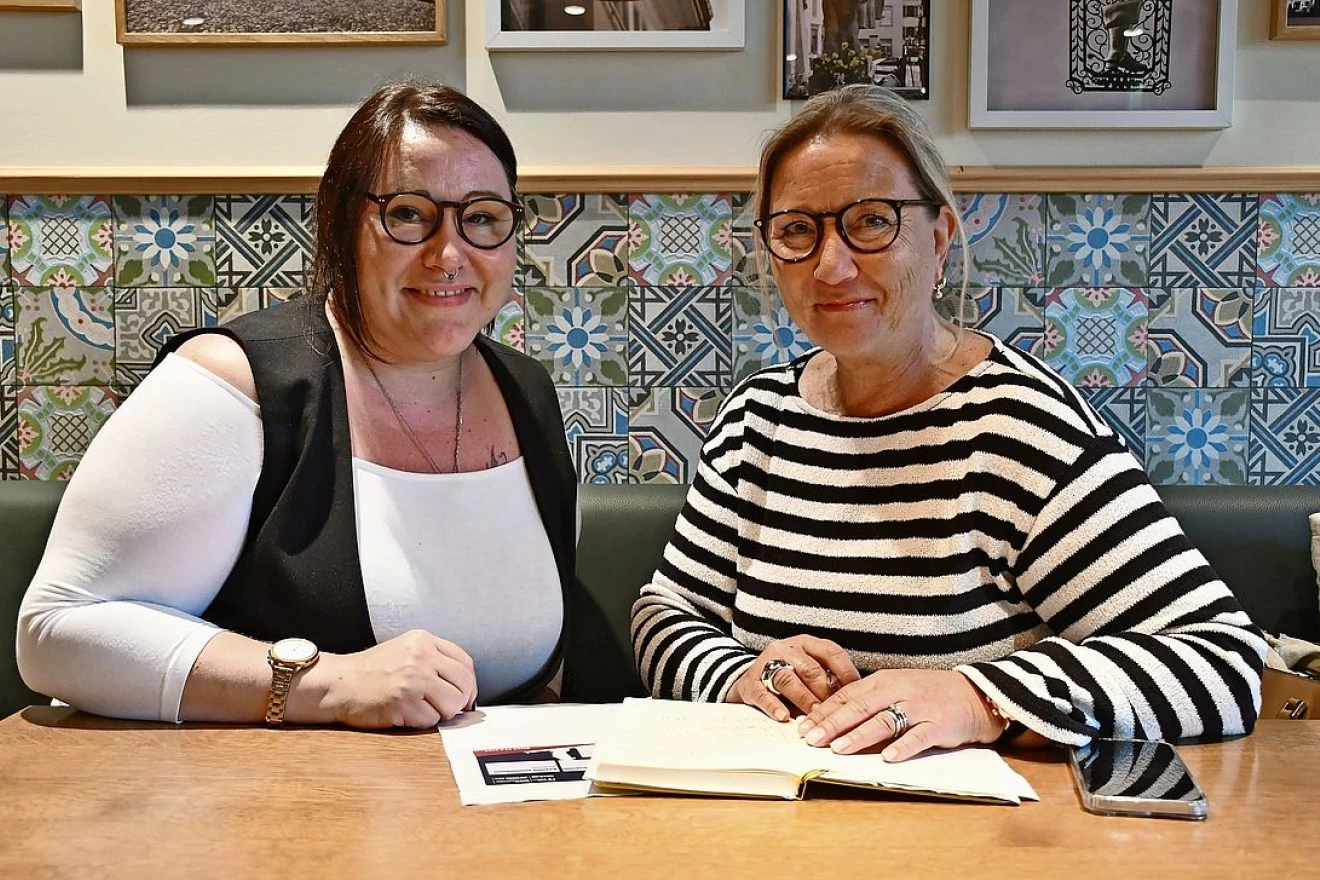 Foto der Freiwilligen Mariann Ebeling mit Mentee Patricia Neumann. Die beiden sitzen in einem Café an einem Tisch. Vor ihnen liegen Notizen zur Besprechung.
