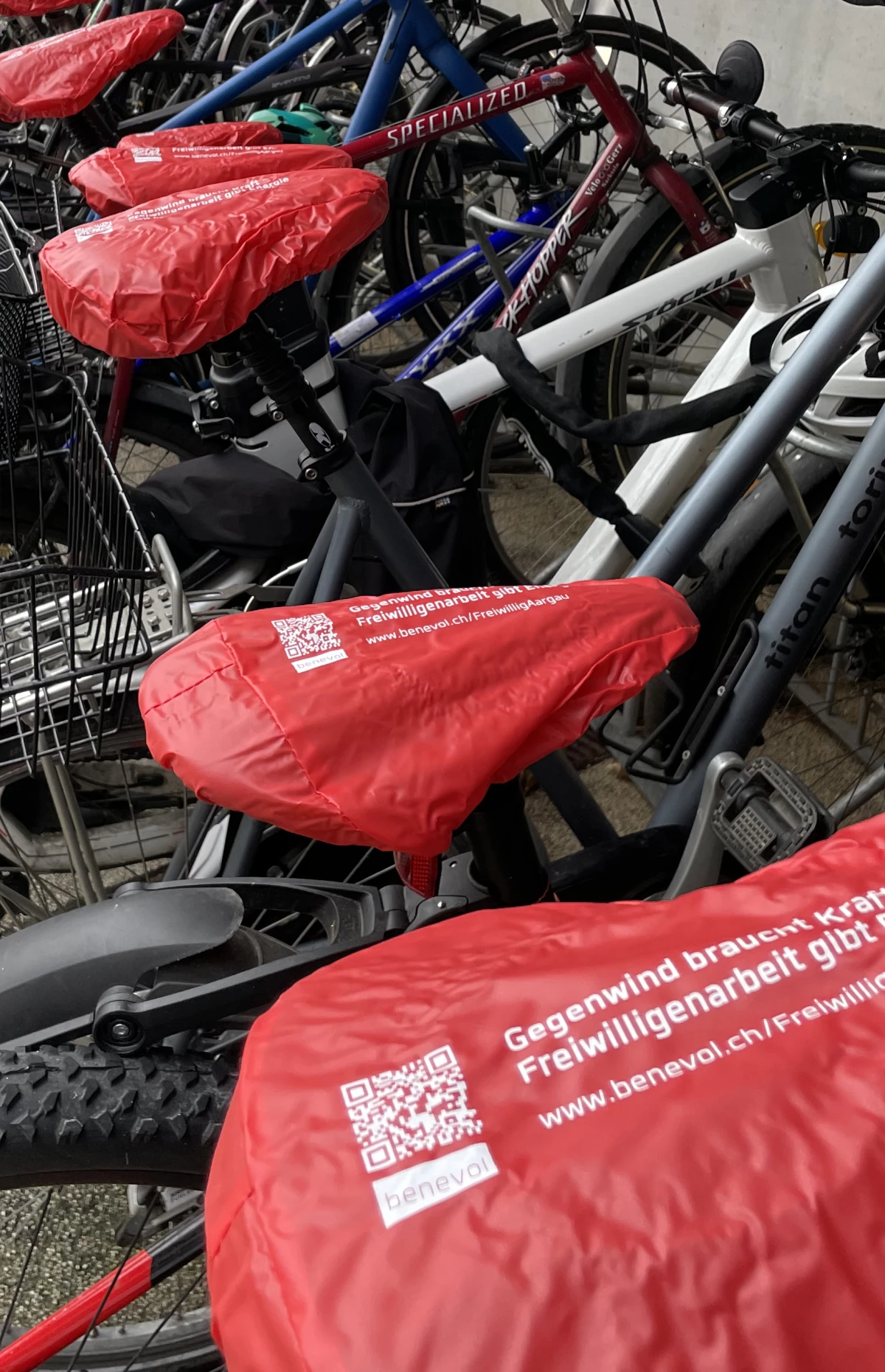 Zu sehen ist eine Reihe parkierter Fahrräder mit einheitlichen roten Sattelüberzügen.