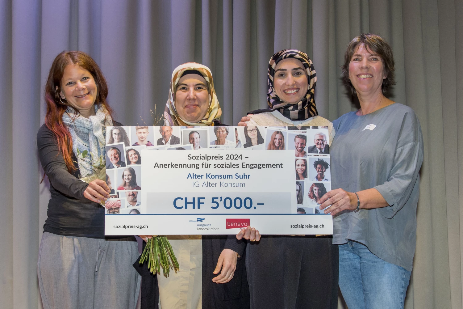 Vier strahlende Frauen halten gemeinsam und stellvertretend für den Alten Konsum einen übergrossen Check, der den Betrag von 5000 Franken zeigt. Der Check symbolisiert ihren Sieg beim Sozialpreis 2024.