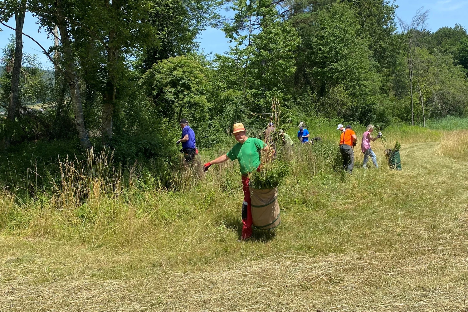 Das Bild zeigt eine Gruppe von acht Freiwilligen bei ihrem Einsatz in der Natur.