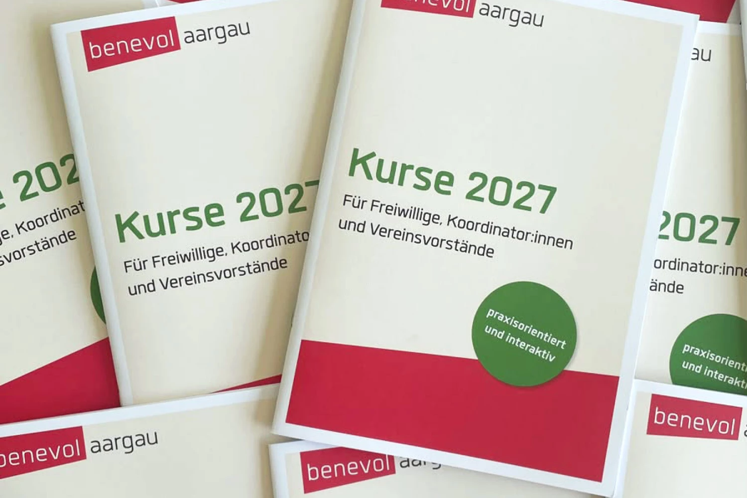 Das Bild zeigt viele Kursprogramme, die auf einem Tisch ausgelegt sind.