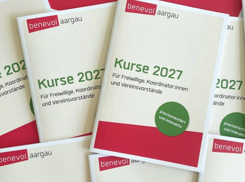 Das Bild zeigt viele Kursprogramme, die auf einem Tisch ausgelegt sind.